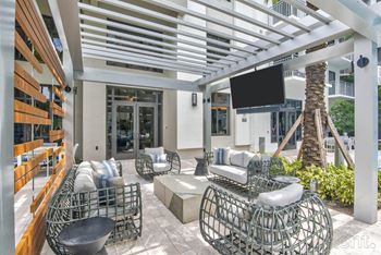 A patio with a white metal chair and a black TV mounted on the wall at Mayla Pompano, Pompano Beach, 33062